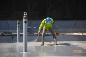 Man Cleaning Flat Metal Roof After Commercial Roof Repairs | Flat Roof | Low Slope Roof | Commercial Roofers | Chandler Roofing