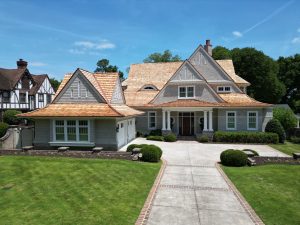Front-facing drone image of a large home with a newly-installed cedar-shake roof | Residential Roofing Projects
