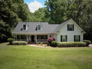 Front-facing image of a white home with a recently-installed granite black ashpalt shingle roof.